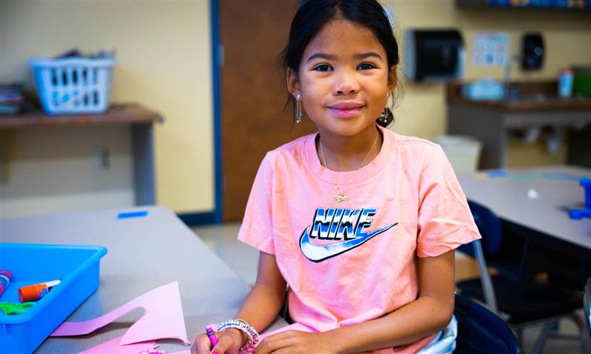 A girl wearing a pink shirt smiles